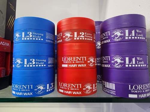 Stacked tubs of Lorenti hair wax in blue, red and purple